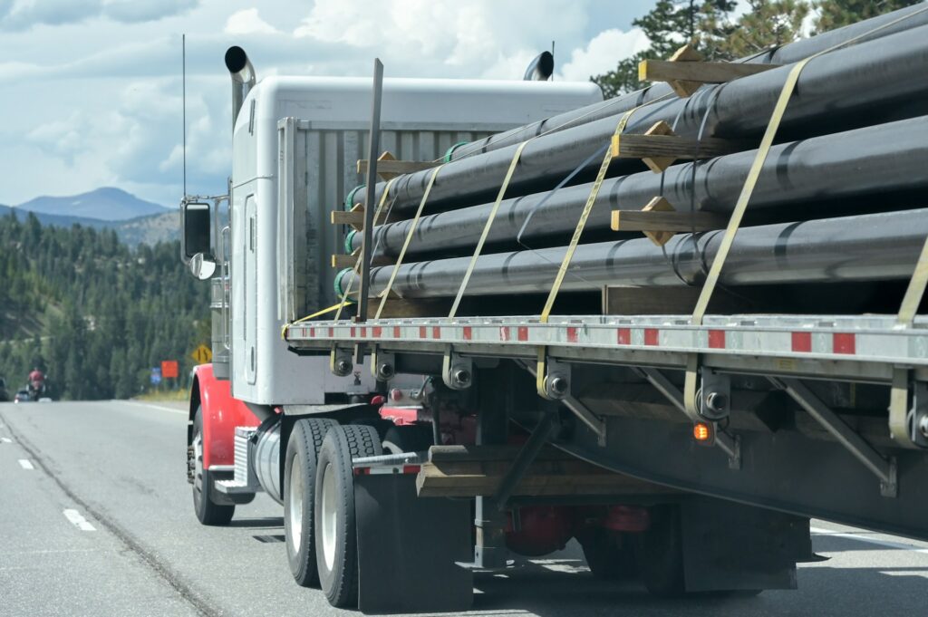 A cargo truck hauling construction pipelines on the highway, representing falling cargo accidents and personal injury claims in Ontario.